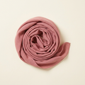 Alessia slim long scarf in dusty rose, coiled on a cream studio backdrop