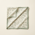 Luciana botanical square scarf in sage and cream, folded on a cream studio backdrop